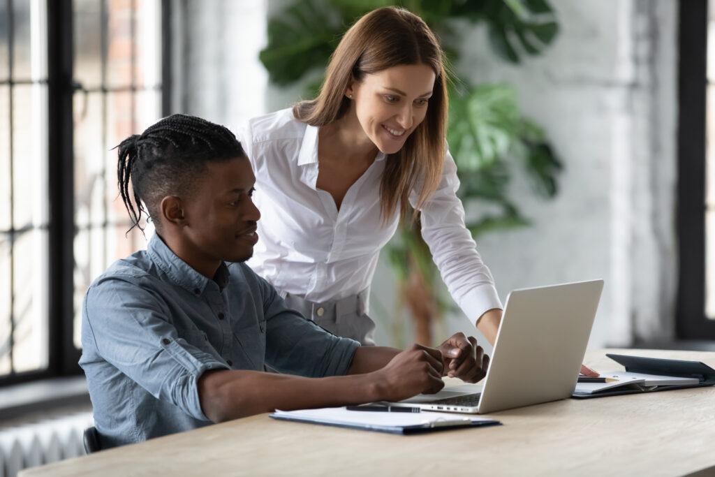 A mentor helping an insurance practitioner apprentice at their desk